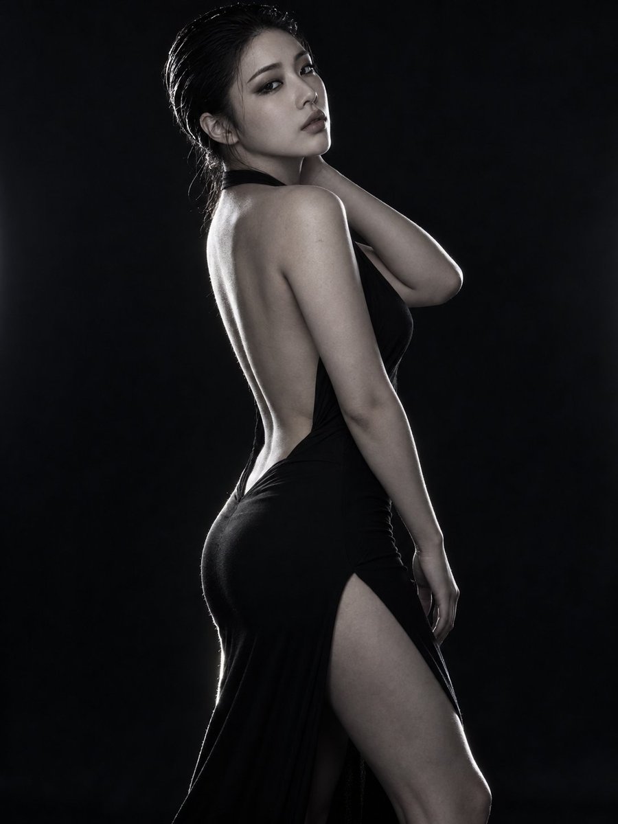 Elegant East Asian Woman in Black Dress Poses Against Dark Studio