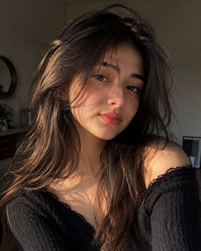 Golden hour sunlight illuminates a woman's face in a cozy bedroom
