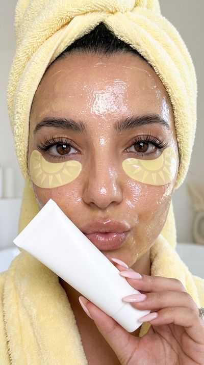Glowing woman holds white tube near lips in butter yellow mask