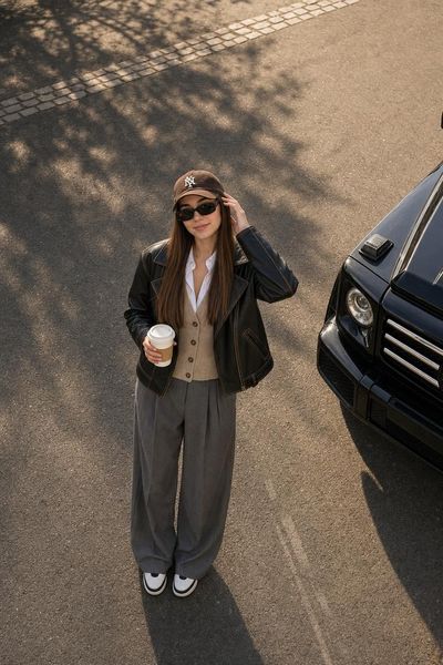 A woman in a leather jacket looks up from the street below