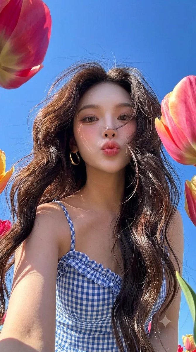 Woman captures cheerful selfie amid vibrant tulips under clear sky