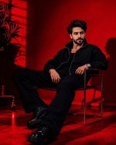 A man in black reclines as red ambition fills the room