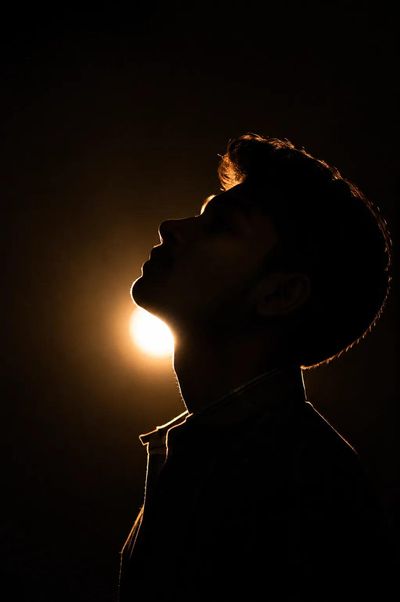 A lone man tilts his head back into warm light