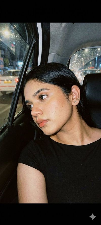 A young woman gazes through a rain-streaked car window at night.
