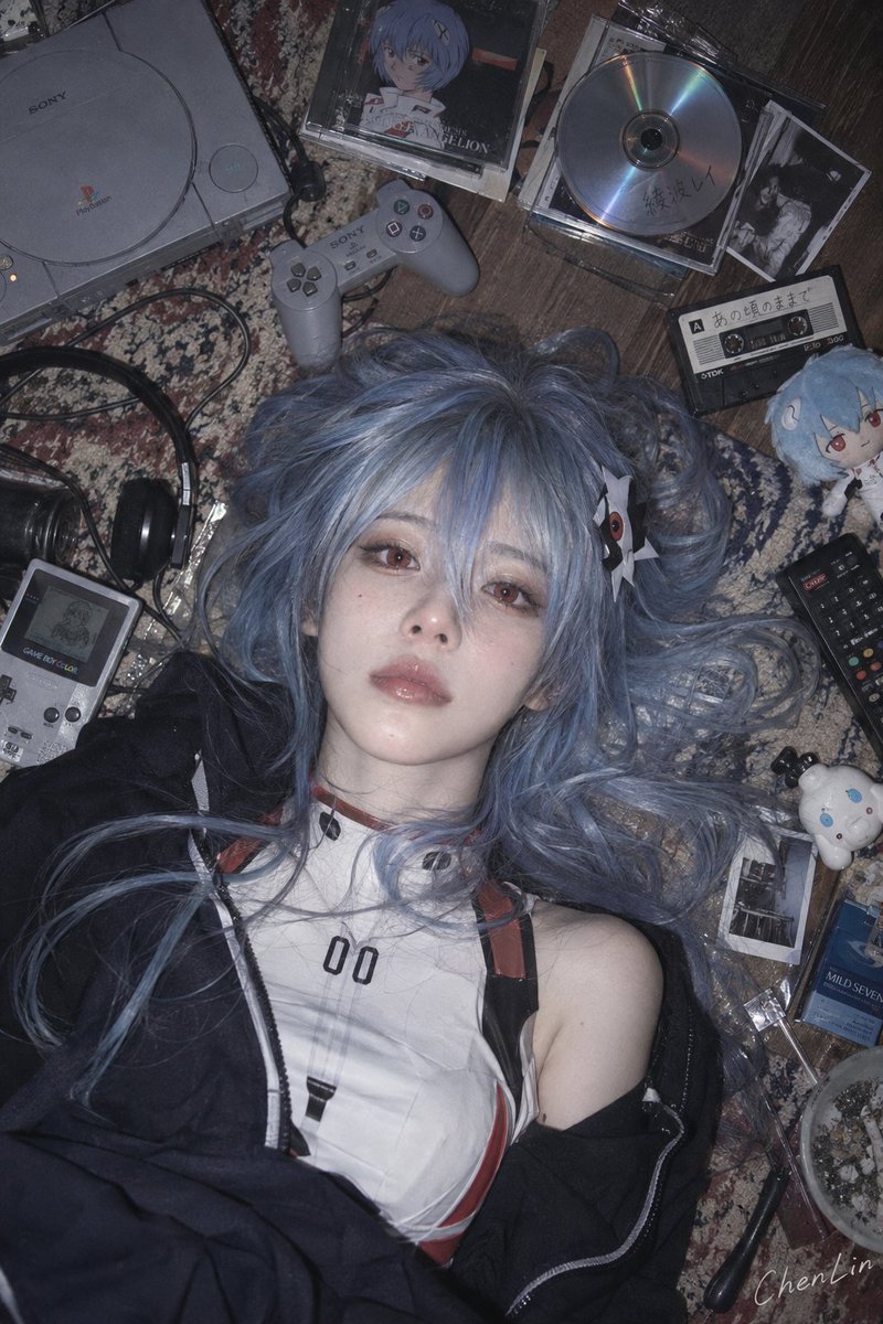 Two cosplay characters lie on a cluttered floor under soft flash
