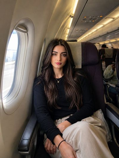 A woman sits calmly by the window in a sunlit airplane cabin