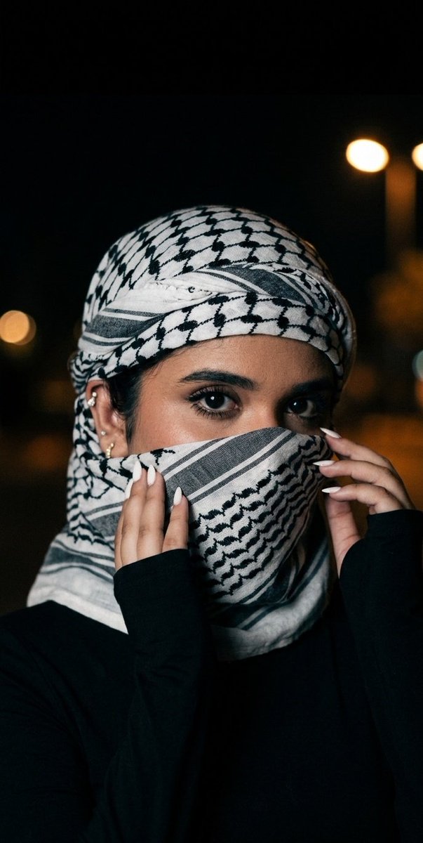 A woman's eyes reveal hidden stories beneath a dark scarf