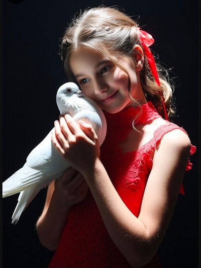 A young girl cradles a white dove in a dramatic portrait