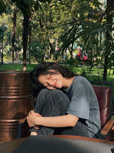 Sunlit East Asian Woman Smiling on a Park Bench