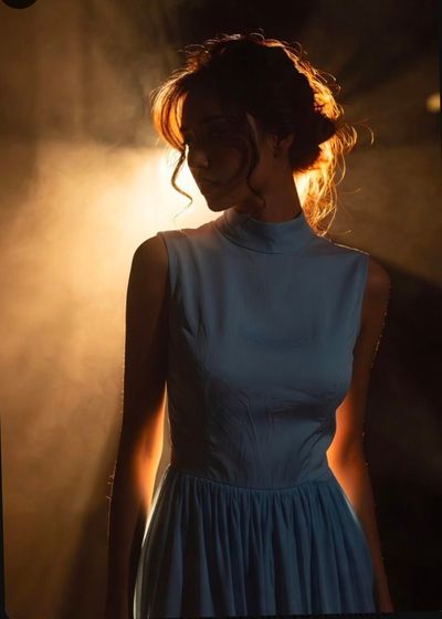 Warm golden backlight shapes a woman's silhouette in smoky haze