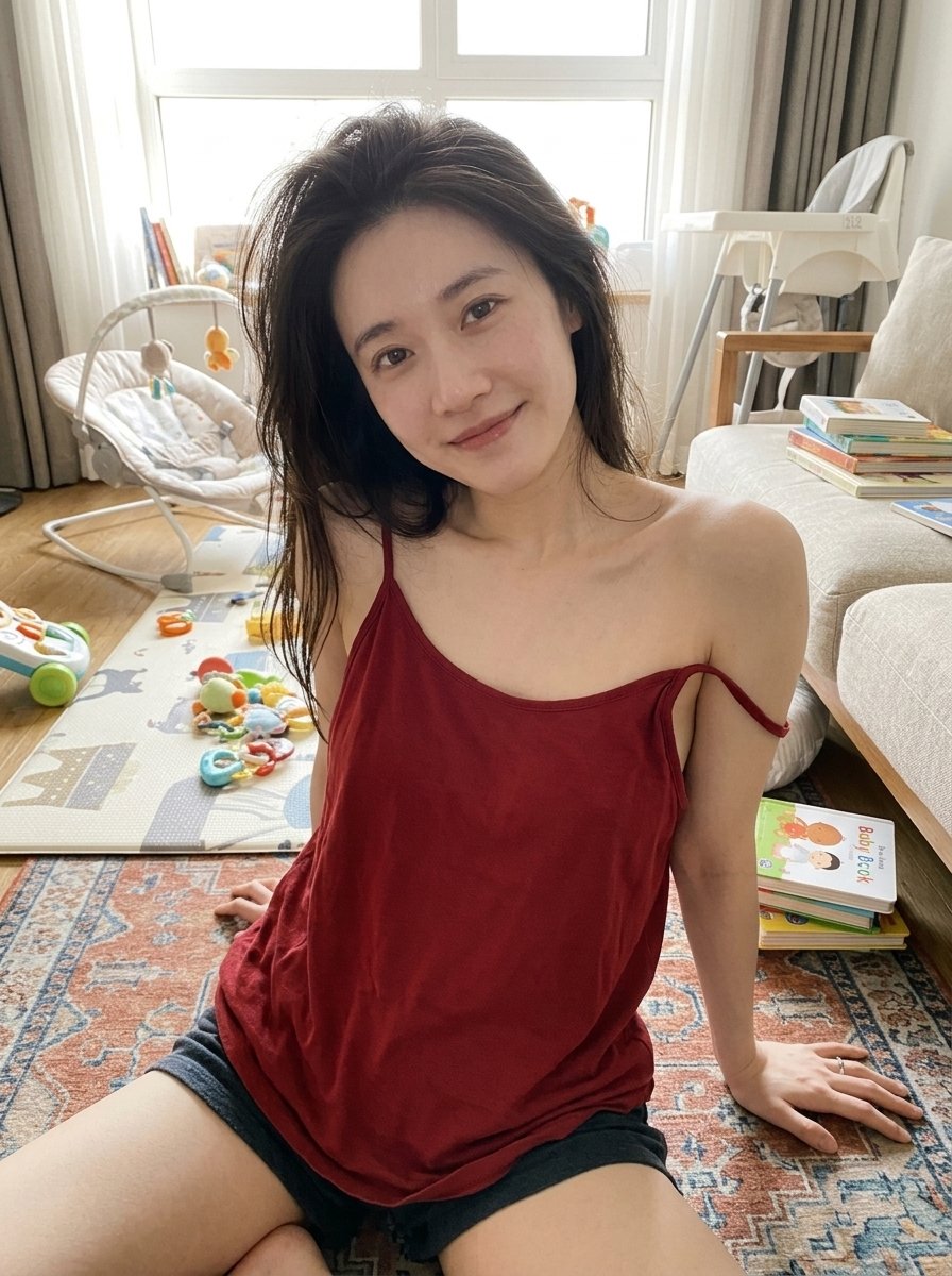Woman in red top leans back in sunlit living room with baby items