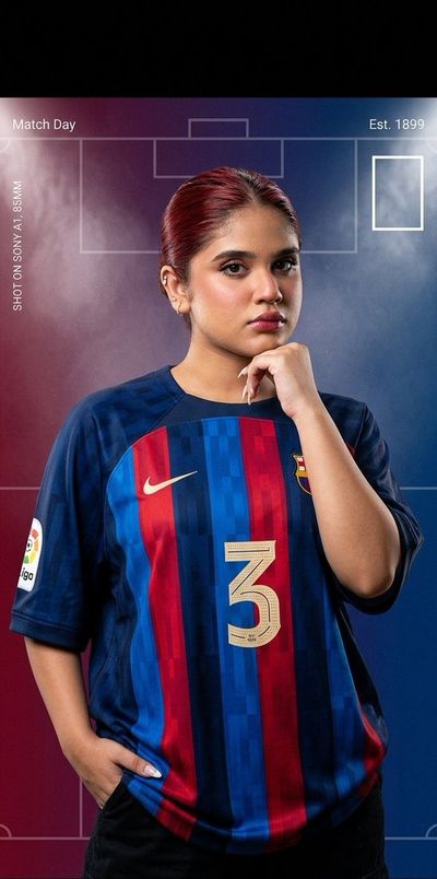 A confident woman in Barcelona jersey poses under stadium lights