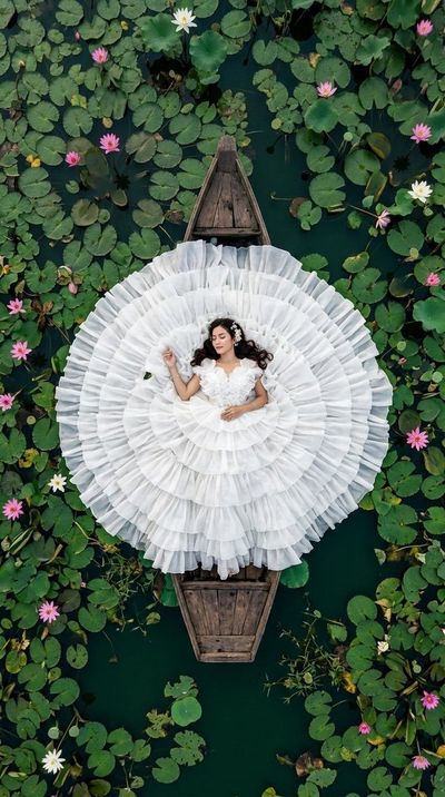 Aerial view shows woman in white gown floating like a lotus flower.