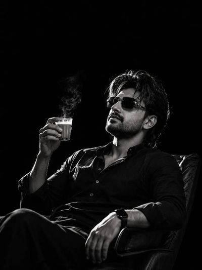 Man reclines in chair sipping steaming chai through dark shades