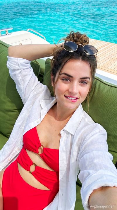 A woman in a red swimsuit reclines on a luxury yacht in sunlight.