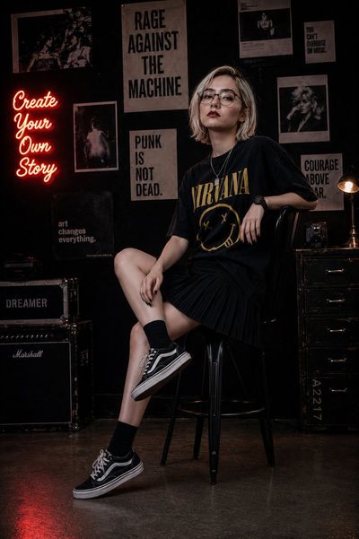 A stylish young woman in a dark music studio sits confidently