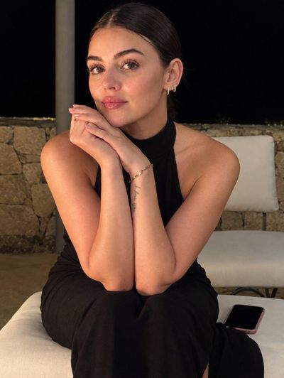 Elegant Young Woman Poses Gracefully on Cream Lounge Chair at Night
