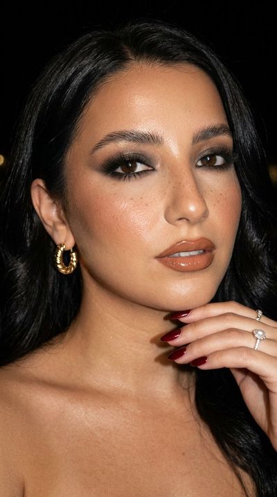 Woman with smoky eyes poses confidently before a formal event