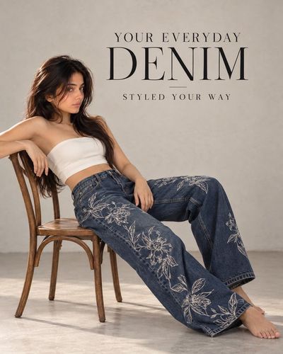 Woman in Embroidered Jeans Reclines on Wooden Chair in Studio