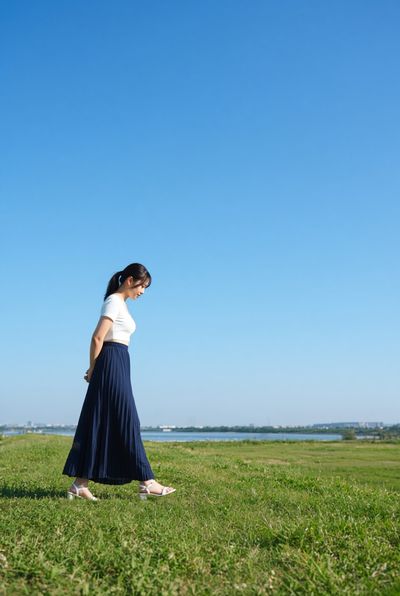 Japanese idol walks riverside in white top and navy skirt