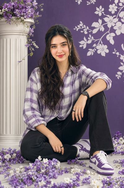 Young woman with voluminous dark hair sits in relaxed pose