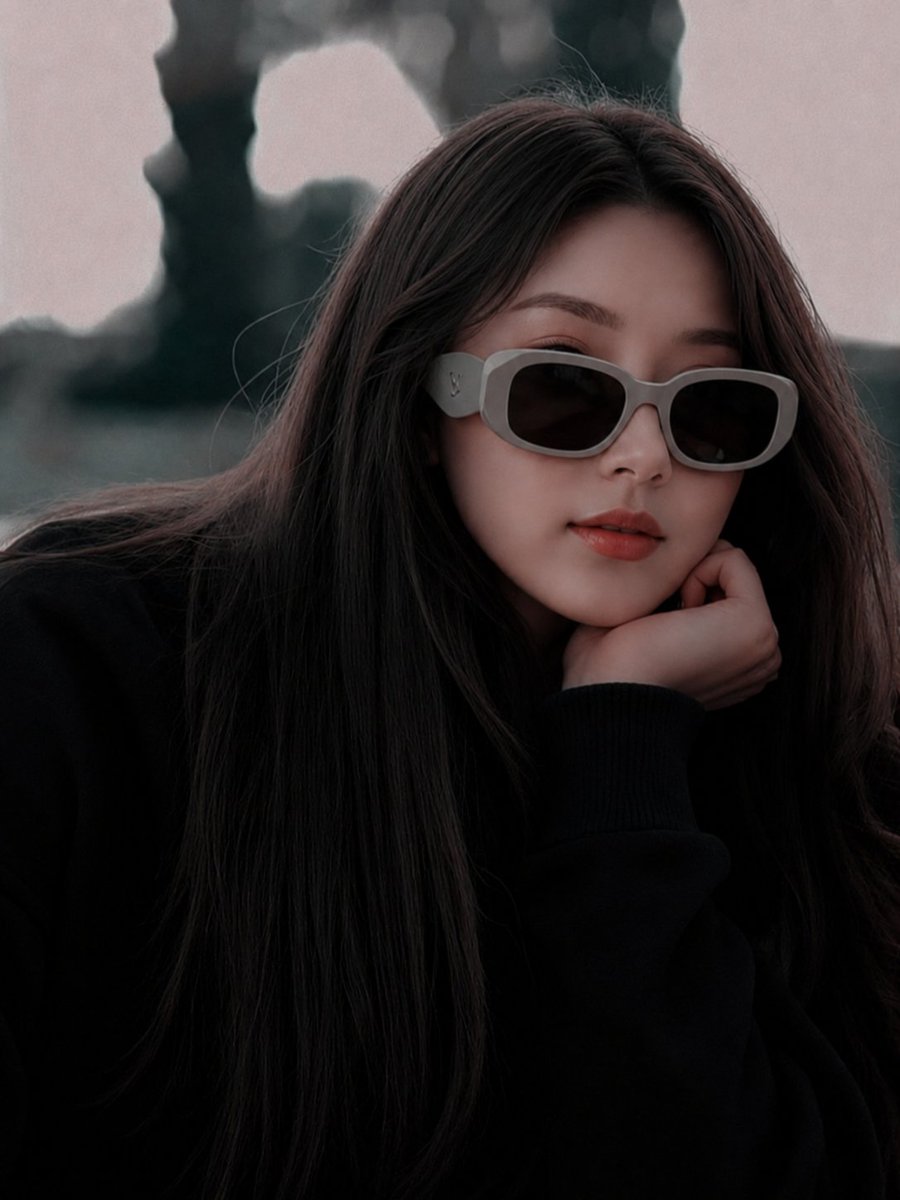 East Asian model in oversized black sweater poses under overcast sky