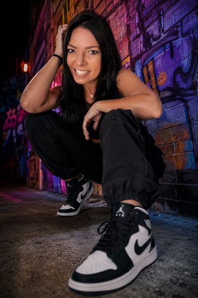 Model crouches in graffiti alley wearing luxury streetwear