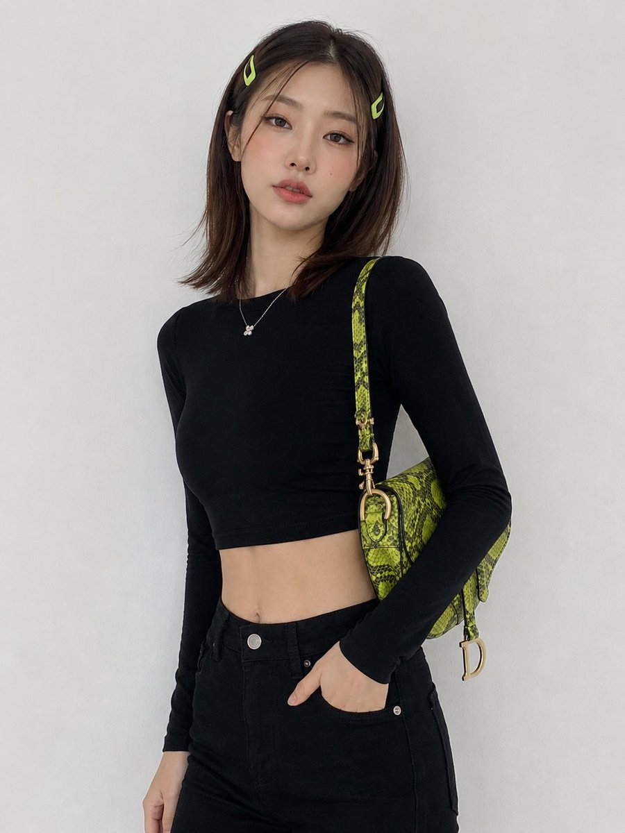 Korean woman in black crops poses with lime green bag against white wall