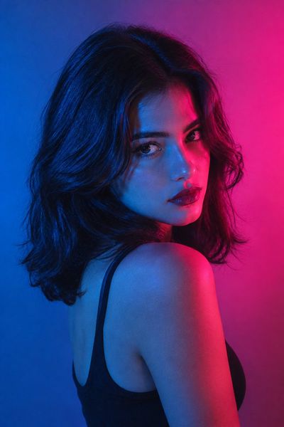 Duotone Gaze: Woman Twists Over Shoulder Under Blue Magenta Gel Light