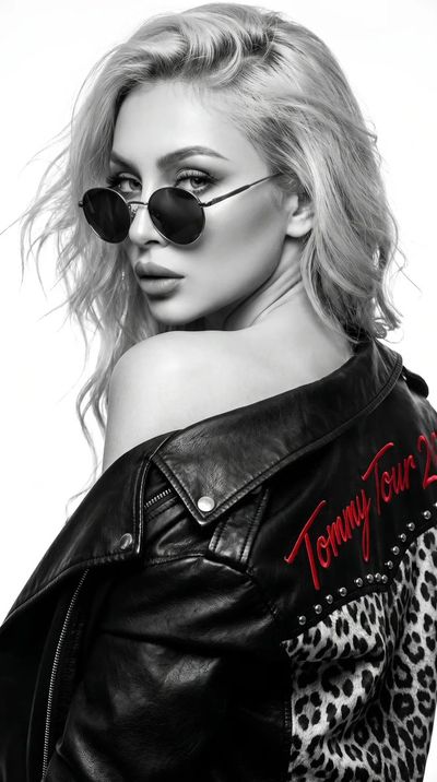 A woman in leather jacket looks back over shoulder with intense gaze