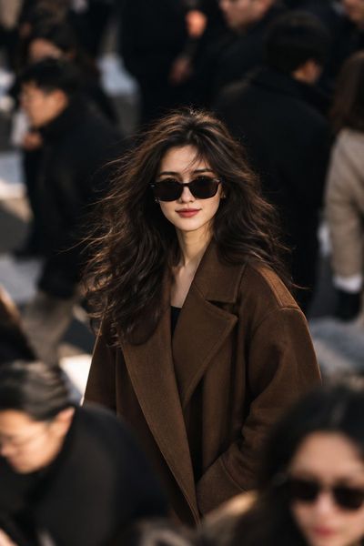 Stylish woman in chocolate coat stands amid busy city crowd