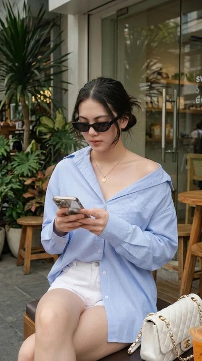 Young woman enjoys iced orange drink at a sunny café