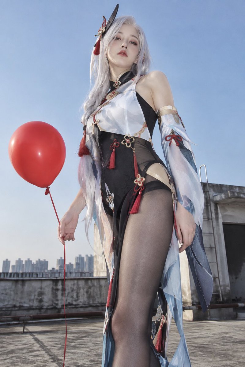 A cool figure gazes down from a city rooftop with a red balloon
