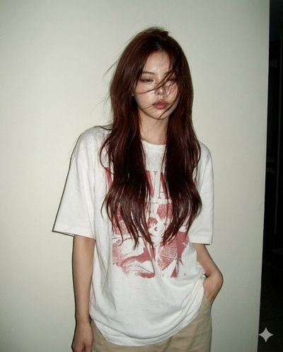 A woman in an oversized tee stands against a white wall