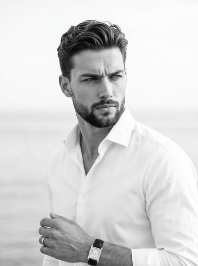 A serious model in white shirt poses against blurred water background
