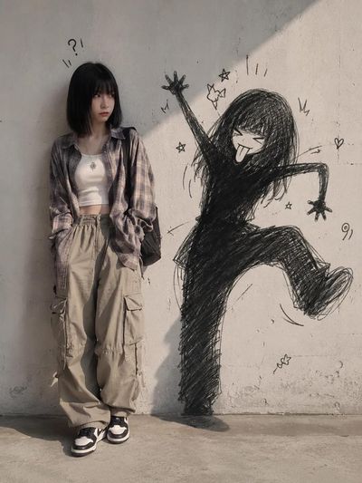 A confused woman in trendy clothes sees her shadow mimicking her poses