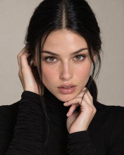 Elegant Woman in Black Turtleneck Poses Under Soft Studio Light
