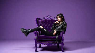 Punk streetwear model lounges on velvet chair in purple void