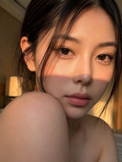 Young woman with bare shoulder turns head in golden hour light