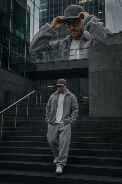A solitary man in grey fleece stands on dark concrete stairs