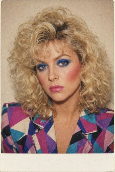A vintage instant film portrait captures a woman with 80s permed blonde hair