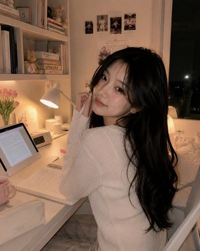 A Korean woman smiles shyly while studying late at night