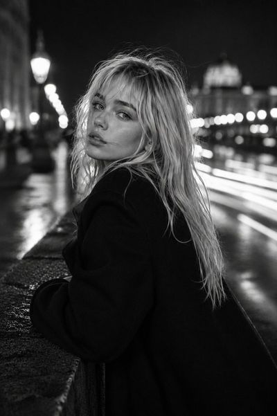 Platinum-haired woman glances back in monochrome city night