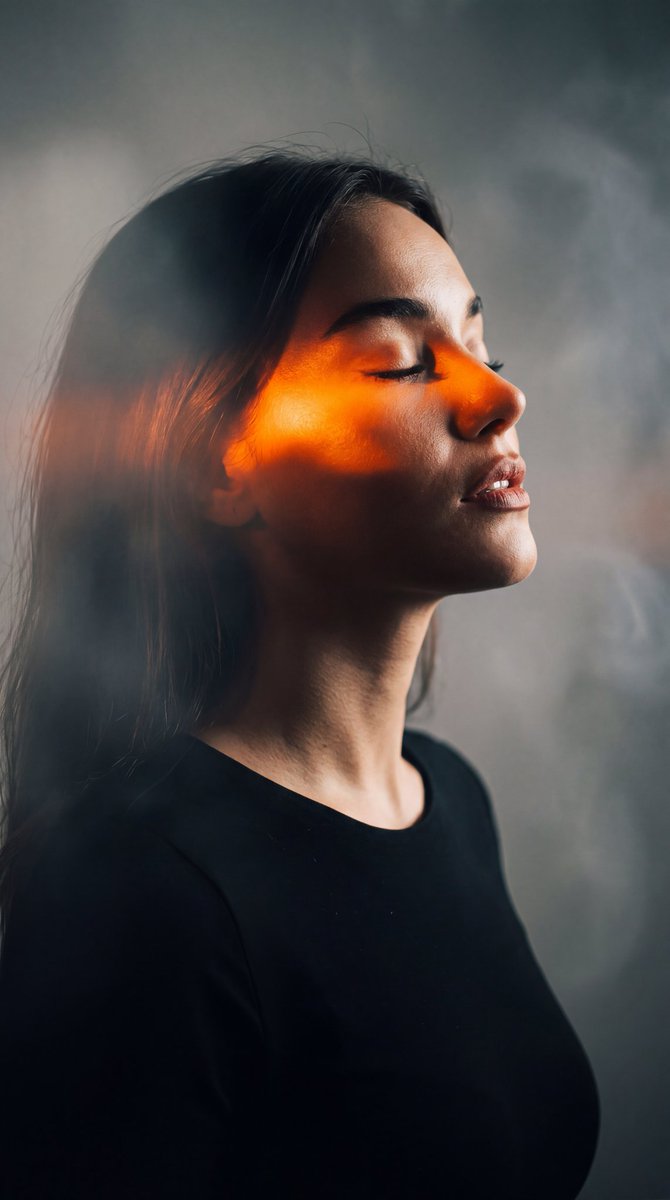 A serene side profile woman glows in orange chiaroscuro light