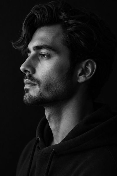 Side profile portrait reveals sharp jawline under dramatic monochrome lighting