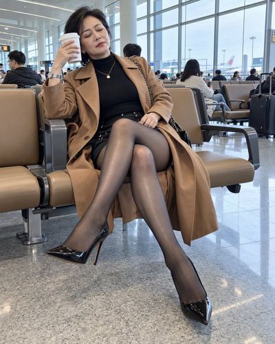 Middle-aged woman rests on airport bench with coffee cup