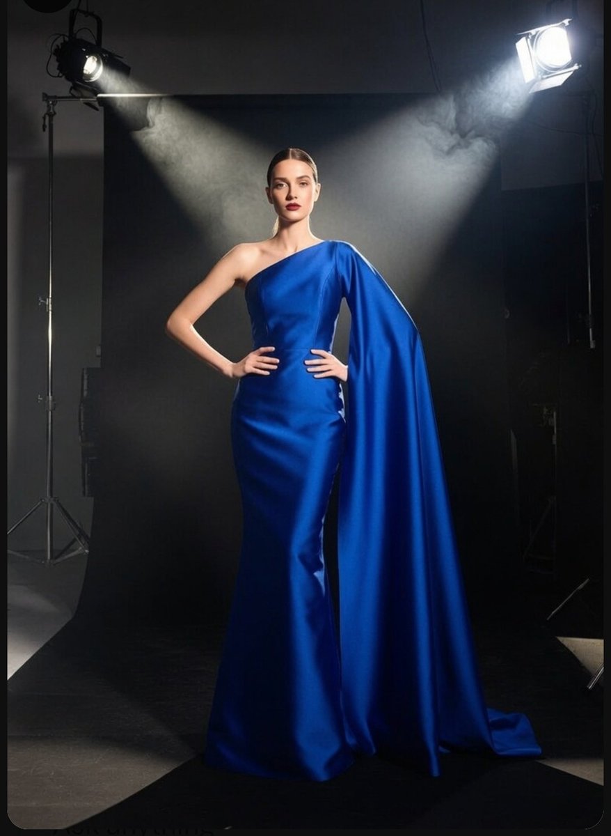 A model in a royal blue gown poses under dramatic studio light