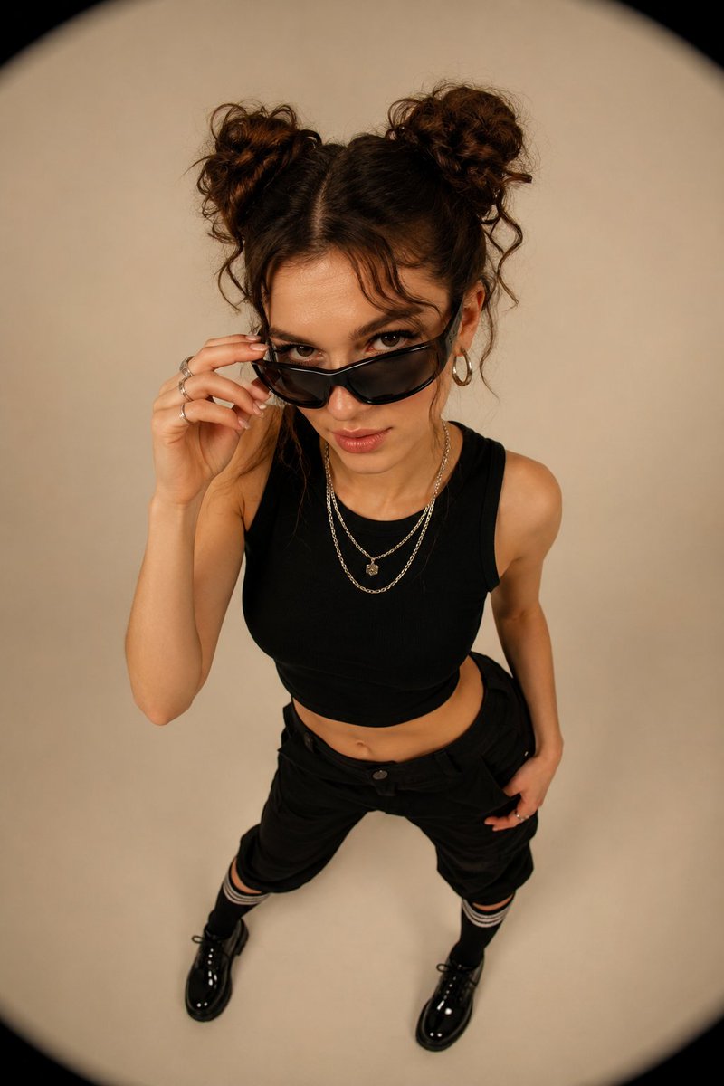 A confident woman adjusts her futuristic sunglasses in a minimalist studio