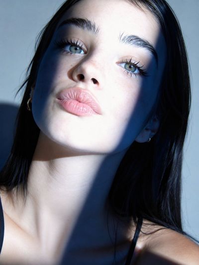 Sunlight casts dramatic shadows across a woman's luminous face