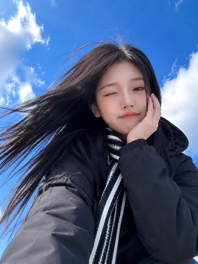 East Asian woman raises fist in a dynamic low-angle selfie